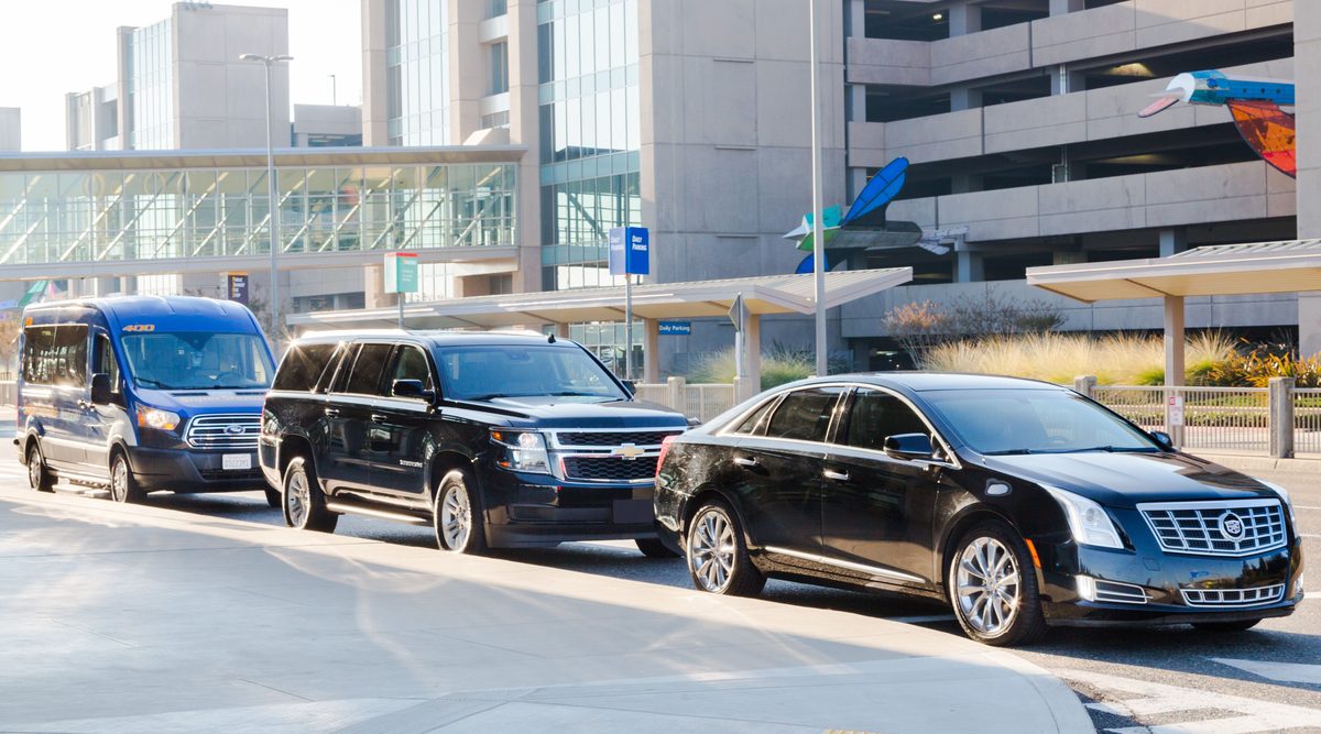 Shuttle van, SUV and sedan waiting at the airport curb